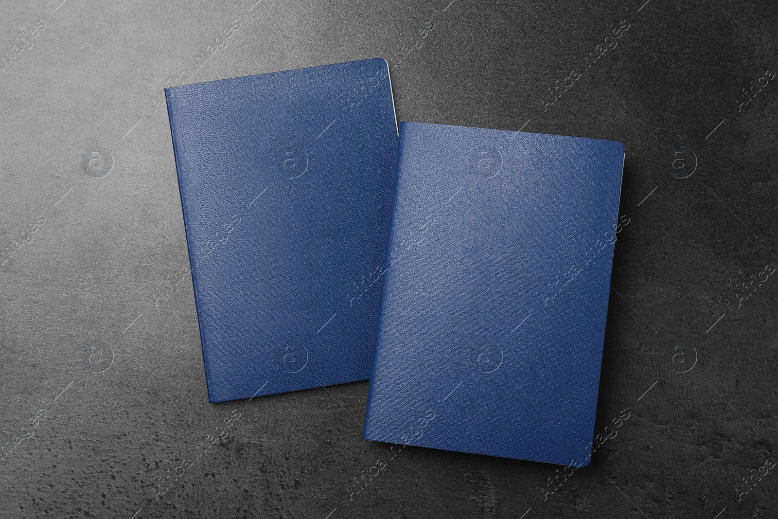 Photo of Blank blue passports on dark grey table, flat lay