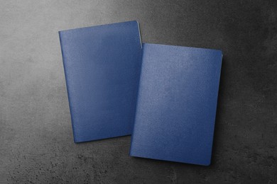 Photo of Blank blue passports on dark grey table, flat lay