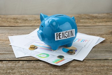Photo of Piggy bank with word Pension, coins and diagrams on wooden table. Retirement savings