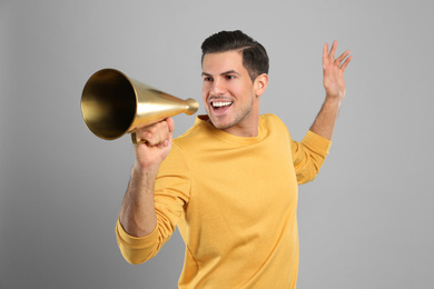 Handsome man with megaphone on grey background