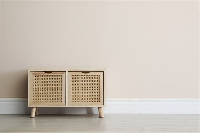 Photo of Wooden chest of drawers near beige wall. Space for text