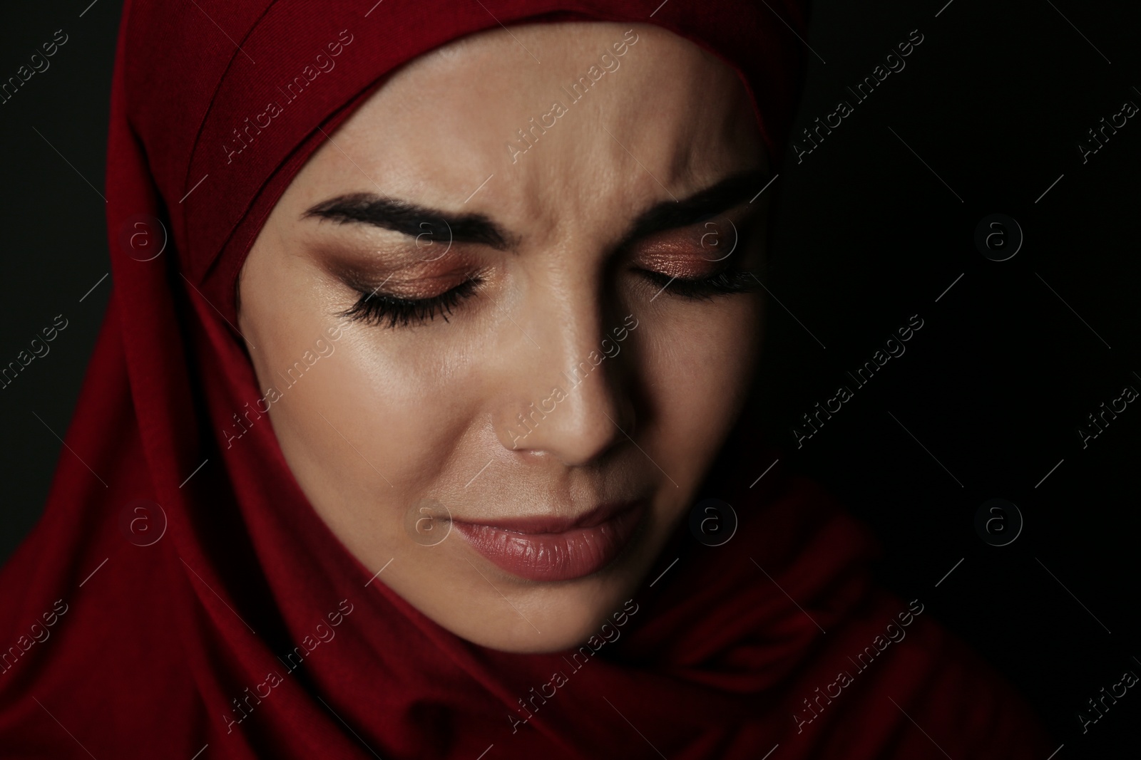 Photo of Portrait of sad Muslim woman in hijab on dark background