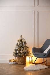 Photo of Beautiful Christmas tree, lantern and rocking chair near wall in room