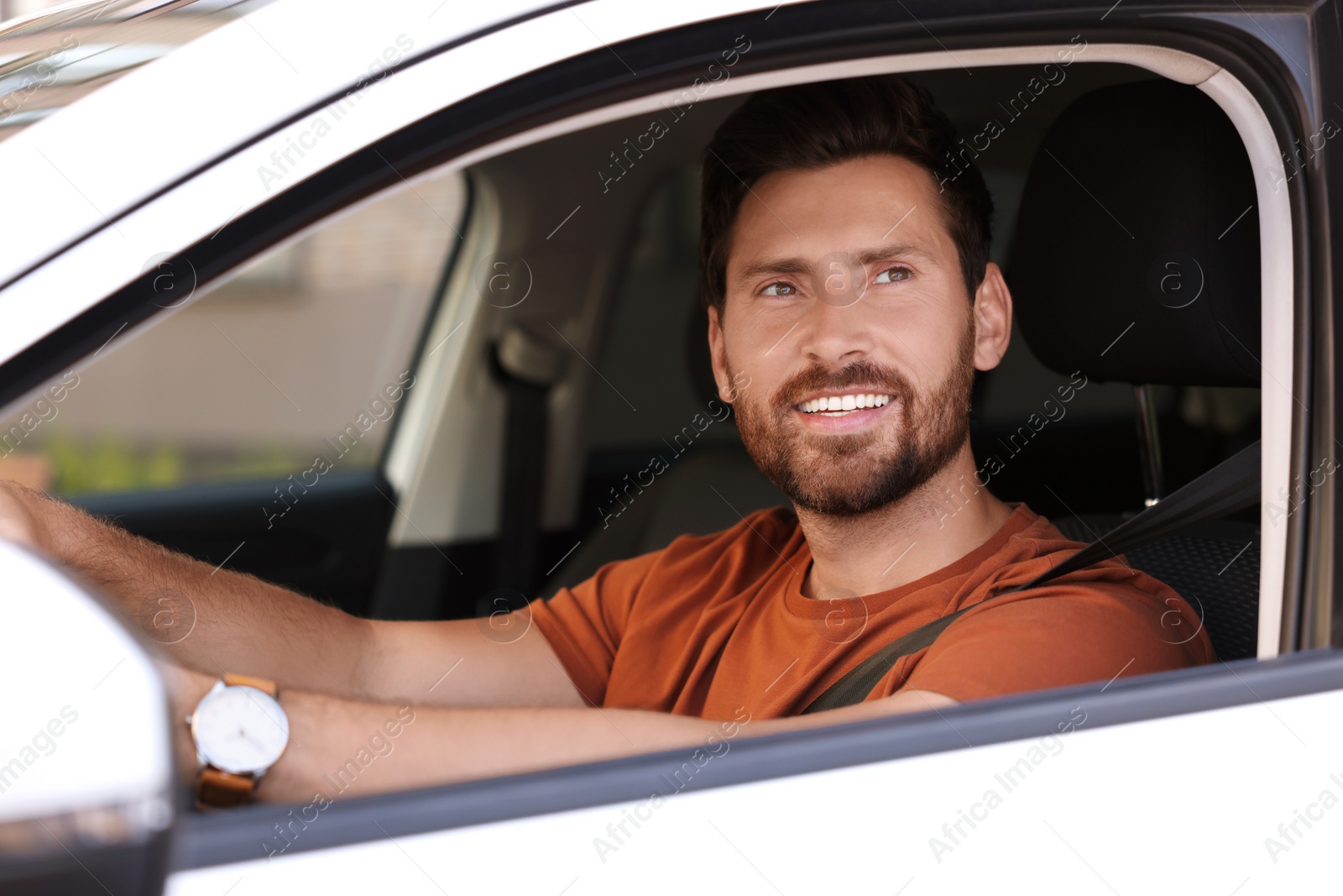 Photo of Enjoying trip. Happy bearded man driving his car, view from outside