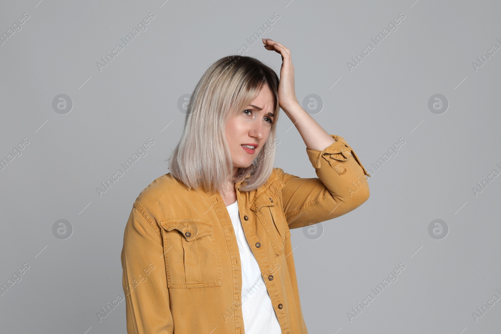 Photo of Woman suffering from headache on light grey background