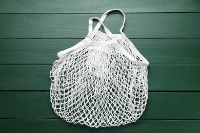 Photo of White string bag on green wooden table, top view