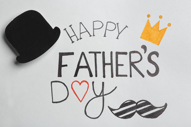 Photo of Paper hat on greeting card with phrase HAPPY FATHER'S DAY, top view