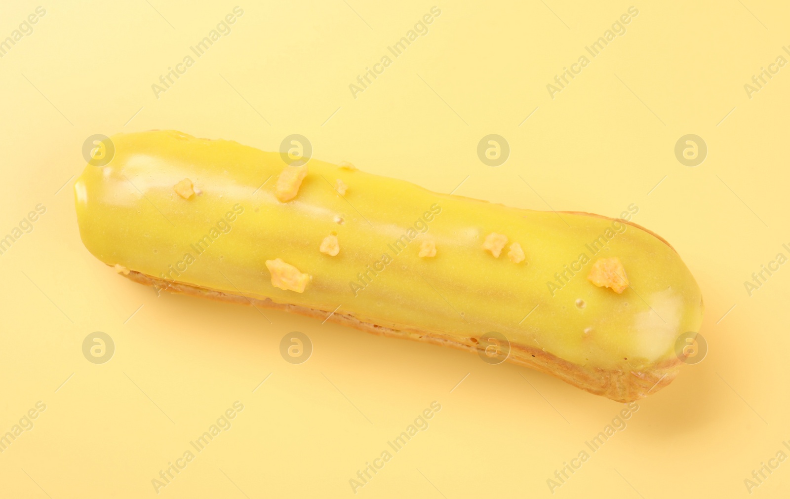 Photo of Delicious eclair covered with glaze on yellow background, top view