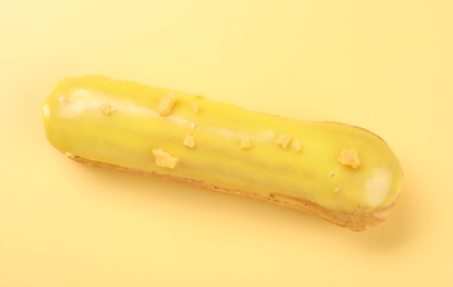 Delicious eclair covered with glaze on yellow background, top view