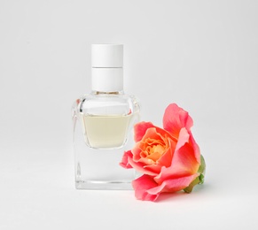 Photo of Transparent bottle of perfume with beautiful rose on white background