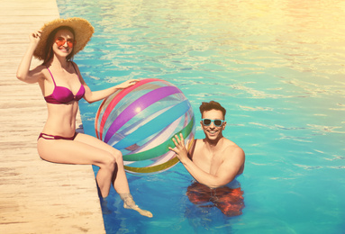 Image of Happy young couple with inflatable ball at swimming pool