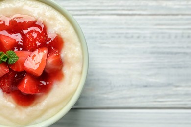 Delicious semolina pudding with strawberries and jam on white wooden table, top view. Space for text