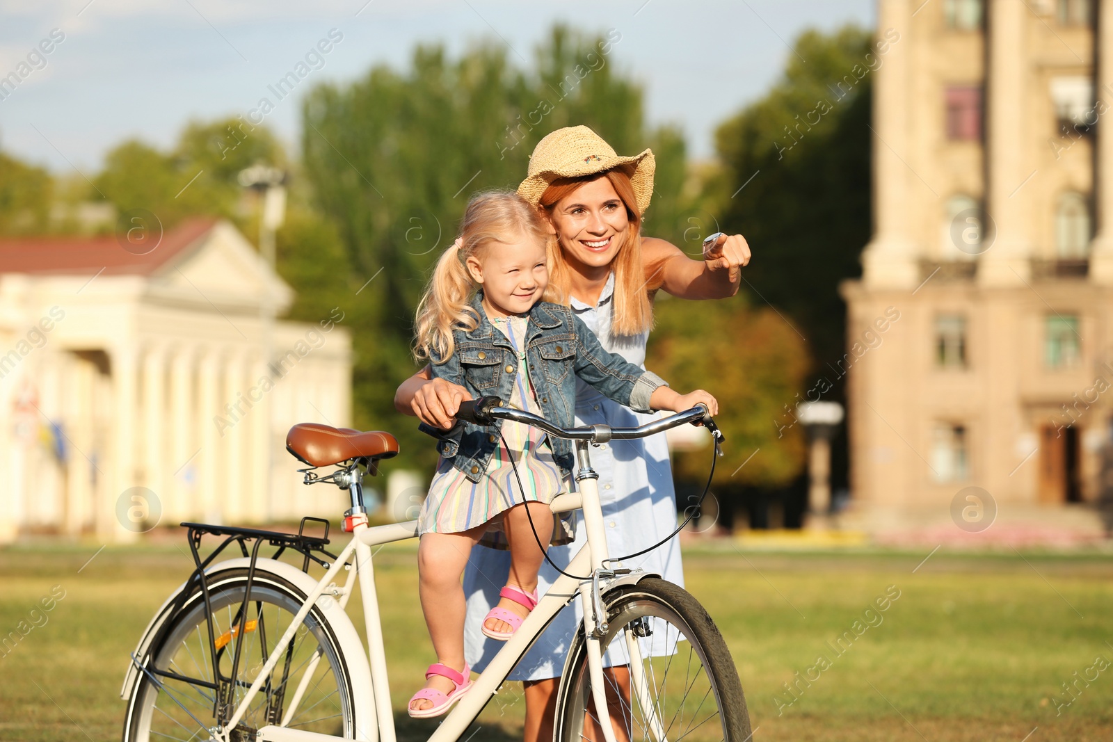 Photo of Happy woman and her little daughter with bicycle outdoors on summer day