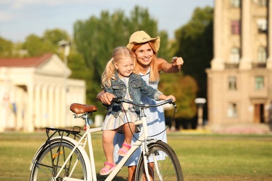 Happy woman and her little daughter with bicycle outdoors on summer day