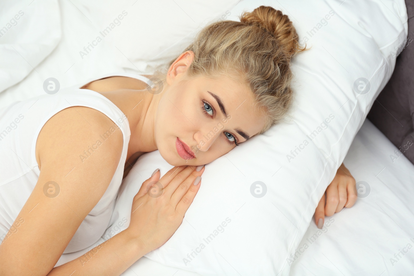 Photo of Beautiful woman lying with comfortable pillow on bed at home