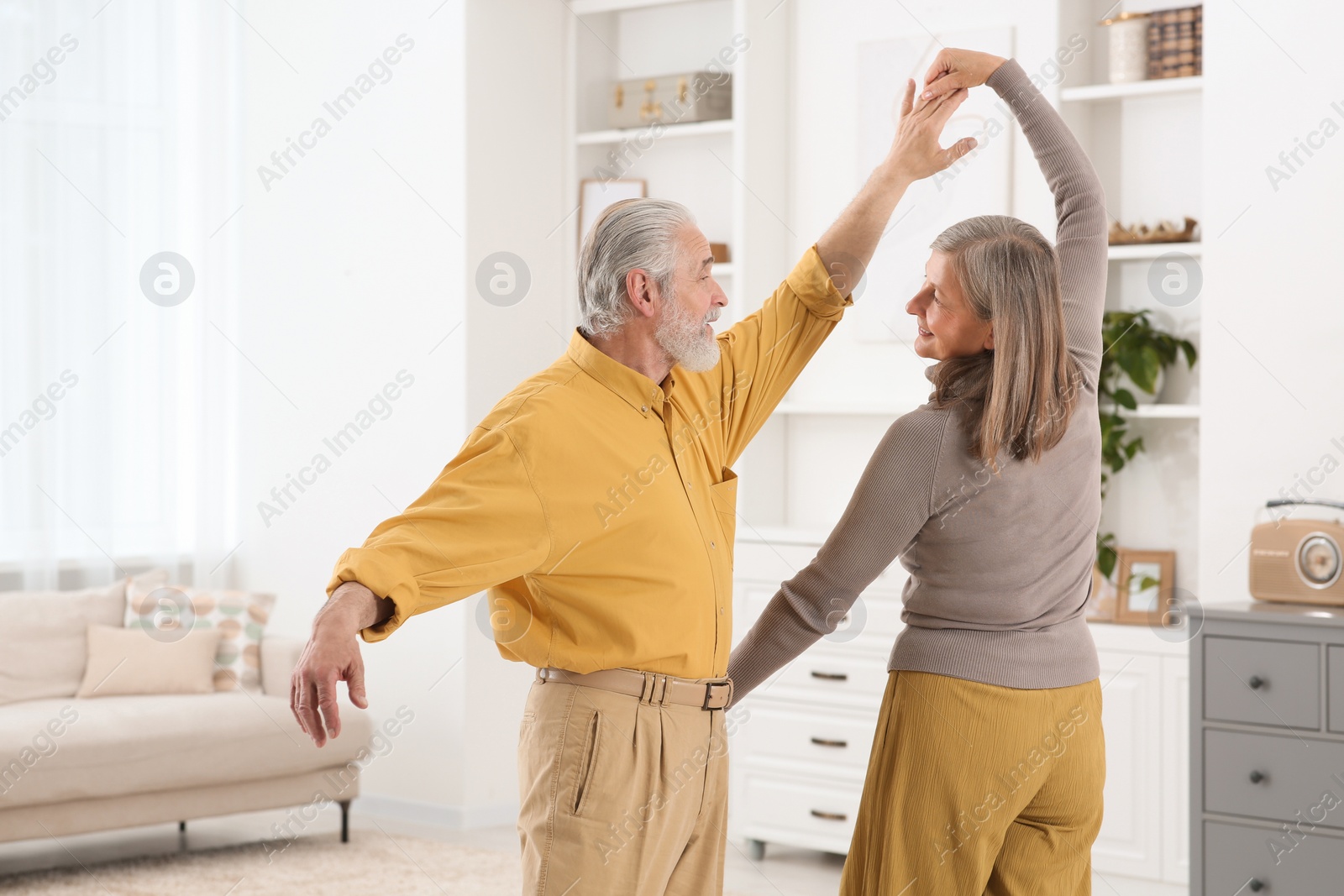 Photo of Affectionate senior couple dancing in living room at home