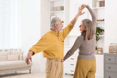 Affectionate senior couple dancing in living room at home