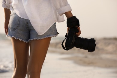 Photographer with professional camera near sea, closeup