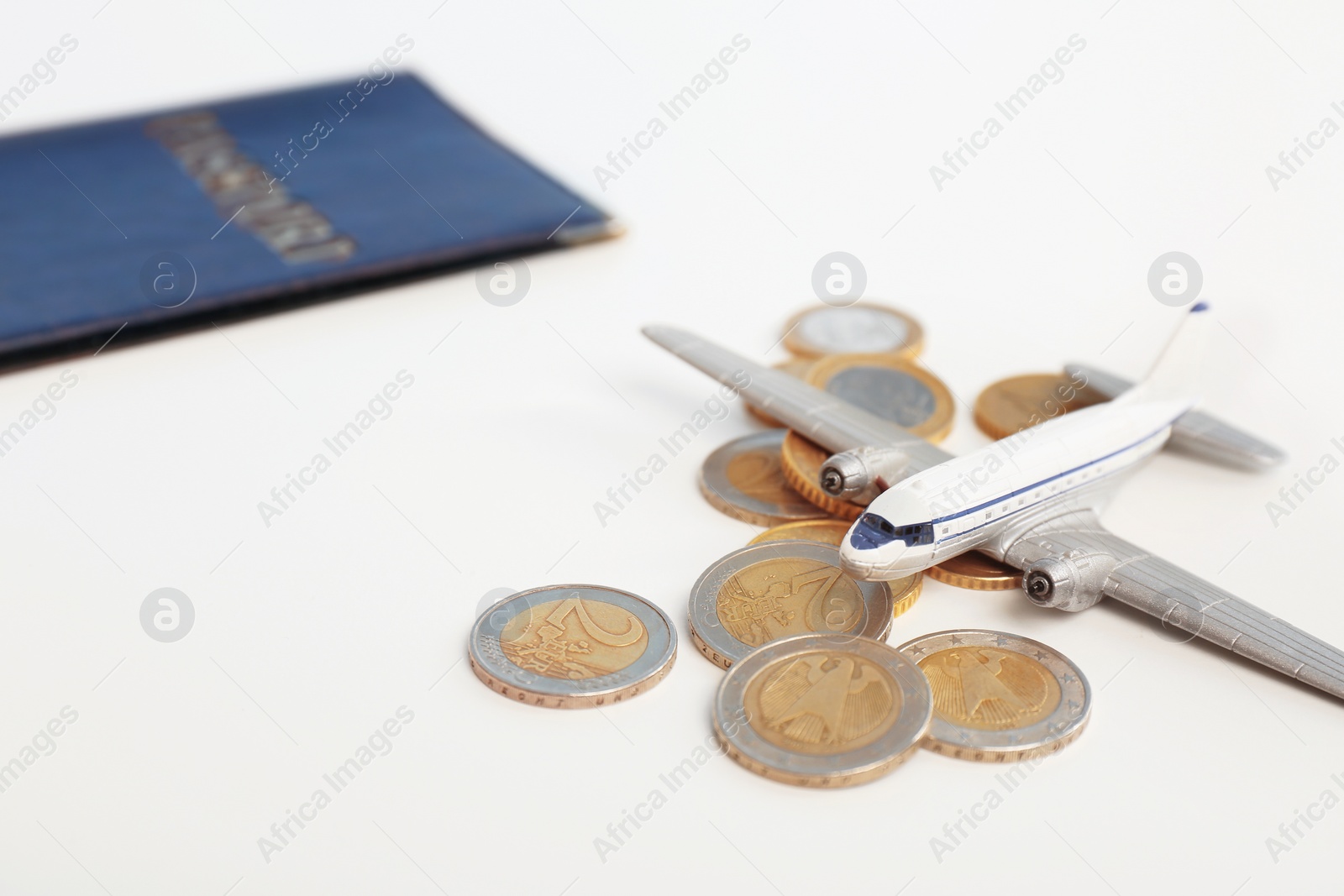 Photo of Toy plane with coins on white background. Travel insurance