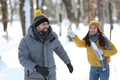 Photo of Happy couple playing snowballs on winter day outdoors