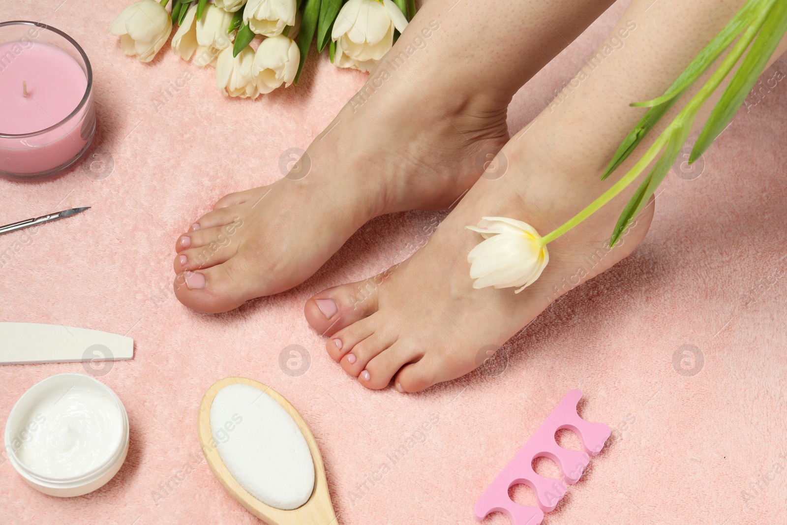 Photo of Woman with neat toenails after pedicure procedure on pink terry towel, closeup