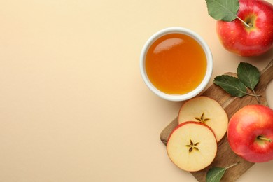 Delicious apples, bowl of honey and leaves on beige background, flat lay. Space for text