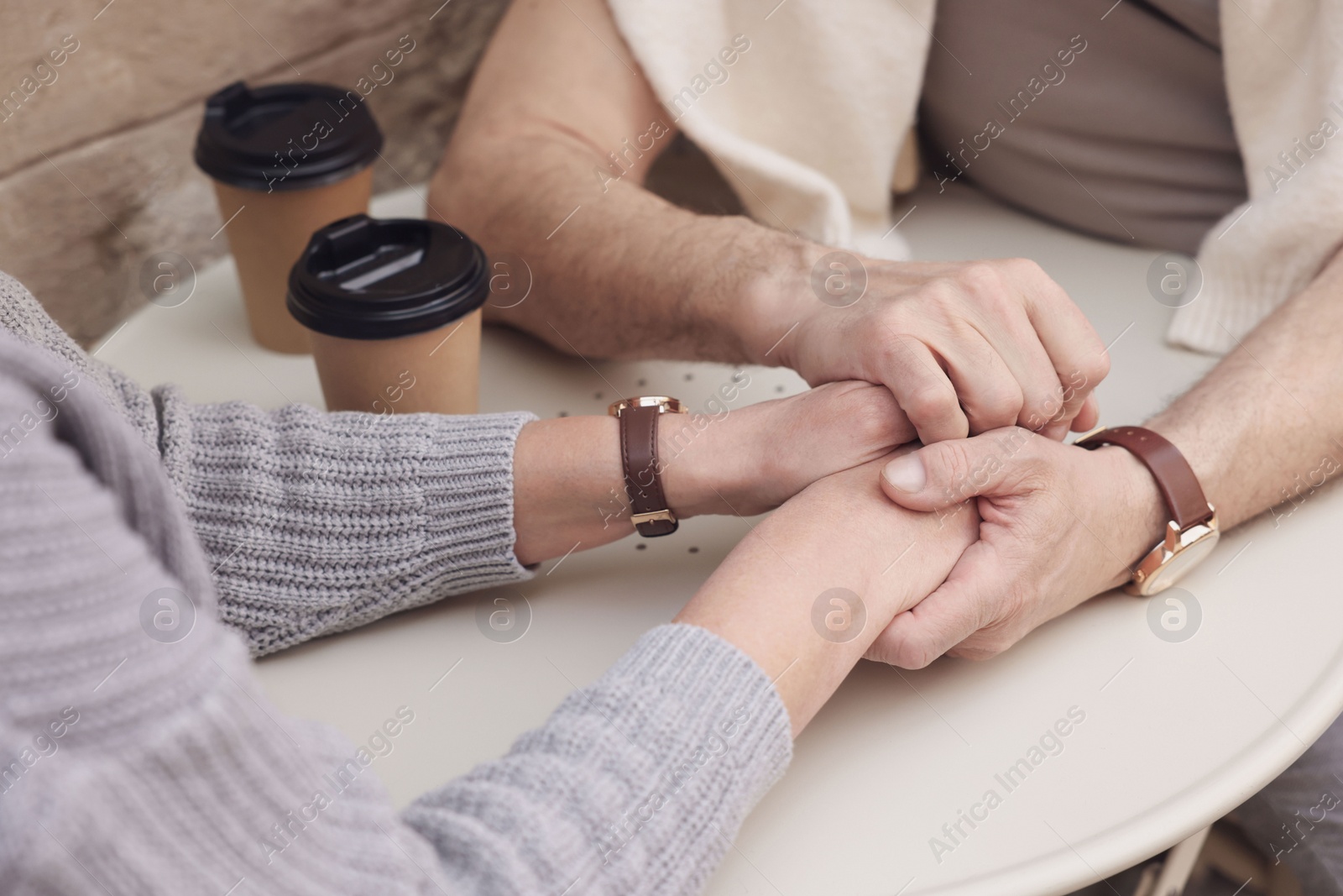 Photo of Affectionate senior couple sitting at table outdoors, closeup