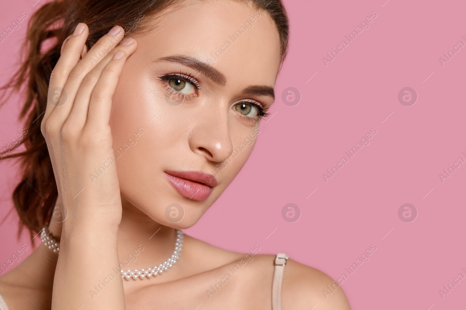 Photo of Young woman wearing elegant pearl necklace on pink background, closeup. Space for text