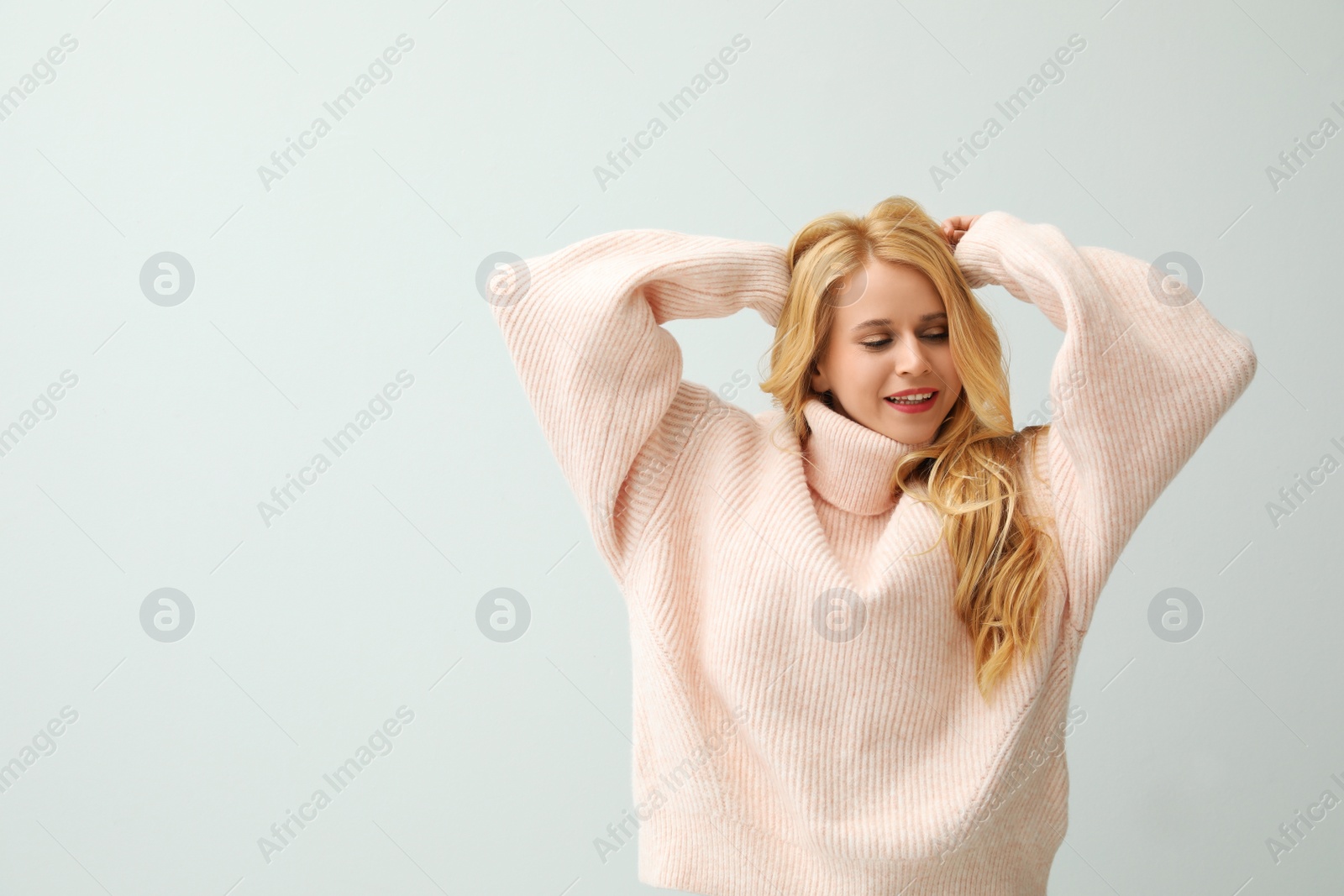 Photo of Beautiful young woman wearing warm pink sweater on white background. Space for text