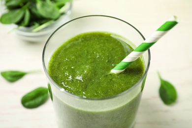 Delicious fresh green juice with straw in glass, closeup