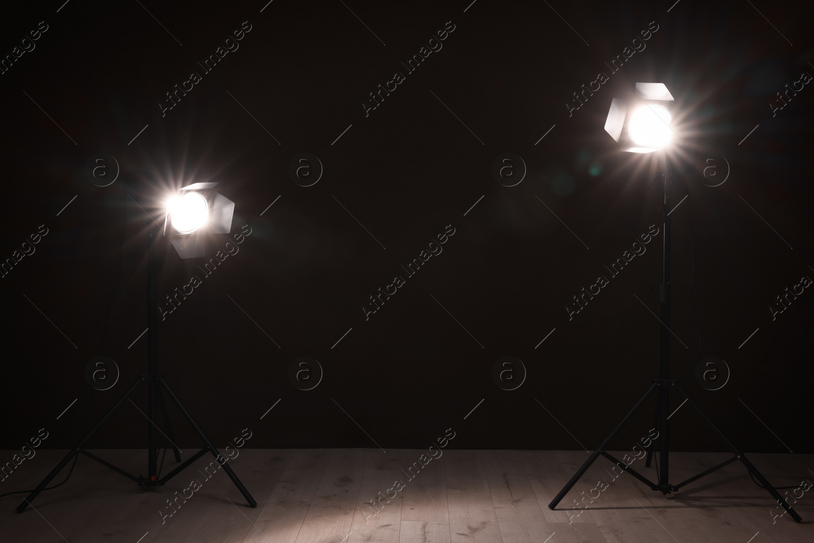 Photo of Bright spotlights near wall in dark room, space for text