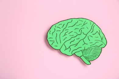 Photo of Paper cutout of human brain on pink background, top view. Space for text