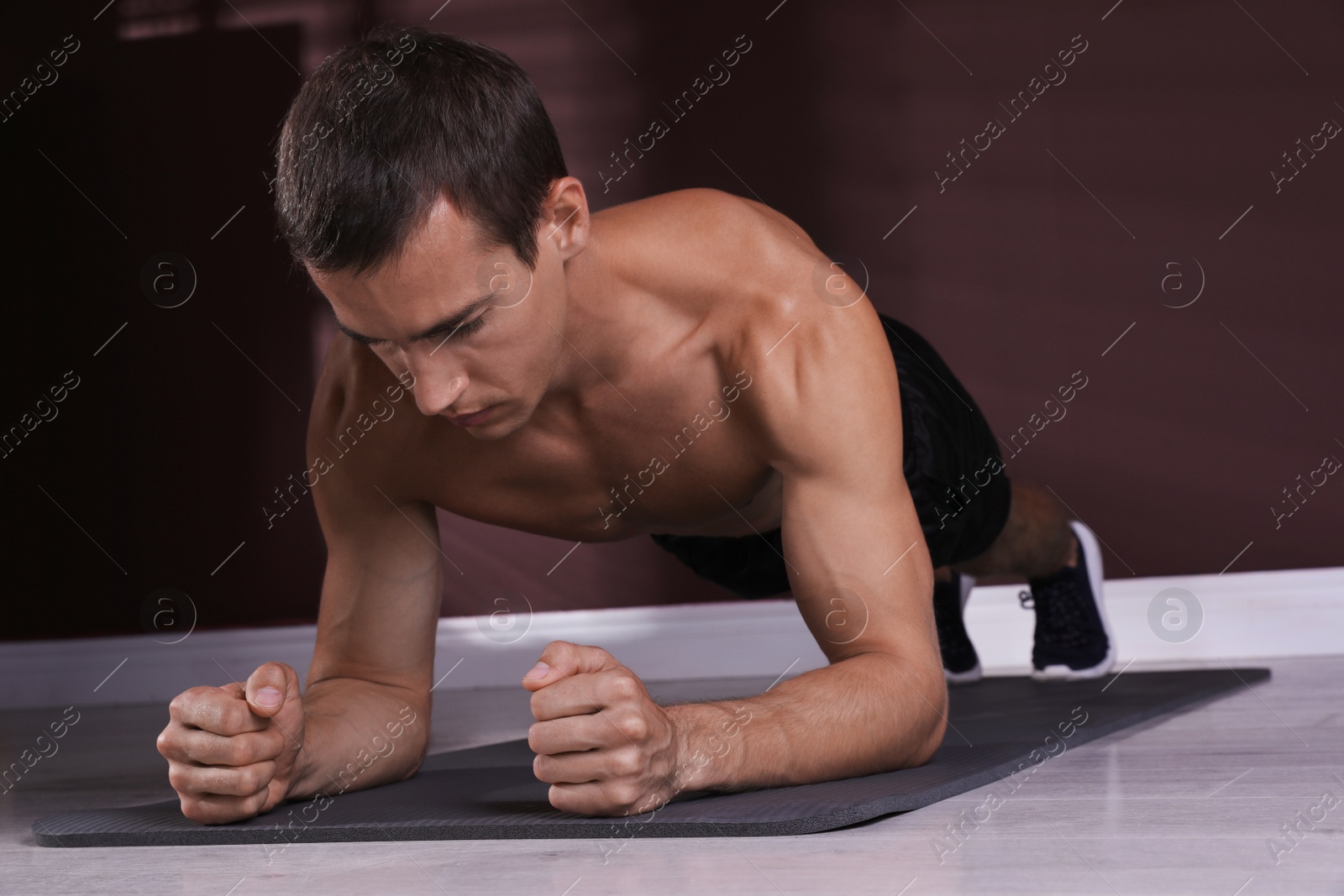 Photo of Handsome man doing plank exercise on floor indoors