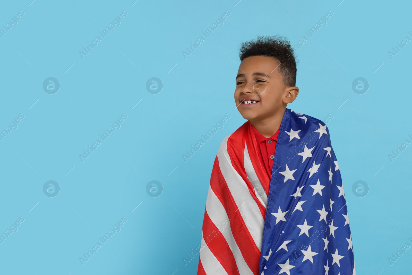 Photo of 4th of July - Independence Day of USA. Happy boy with American flag on light blue background, space for text