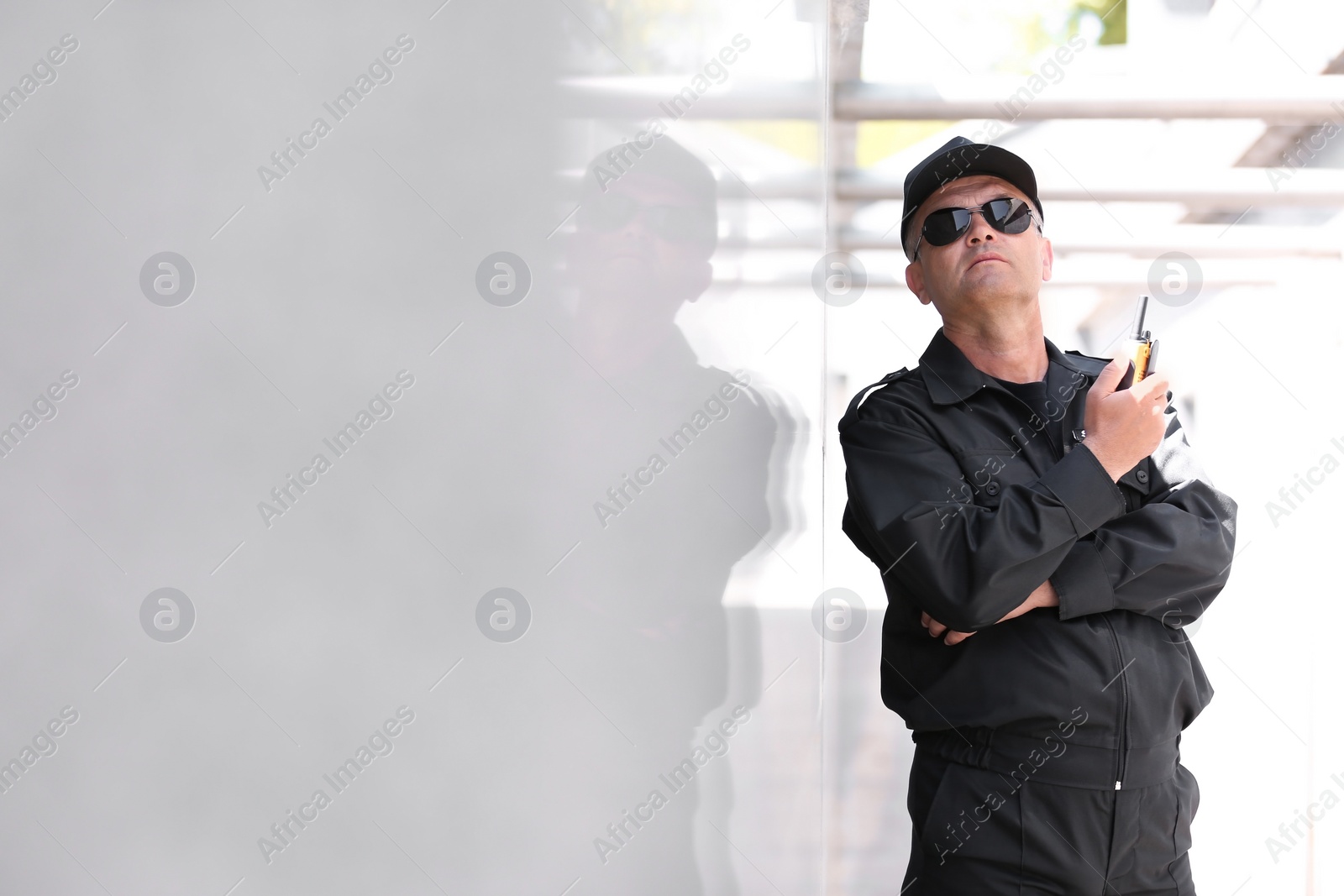 Photo of Male security guard using portable radio transmitter outdoors