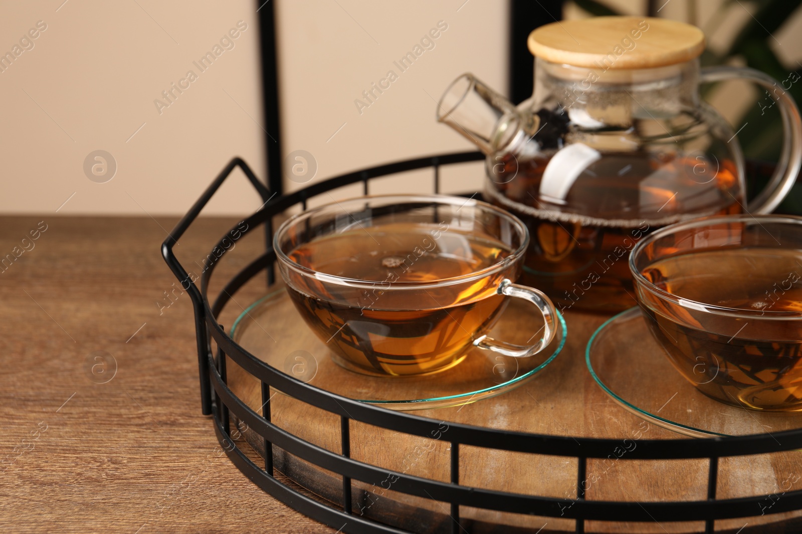 Photo of Aromatic tea in glass cups and teapot on wooden table, closeup. Space for text