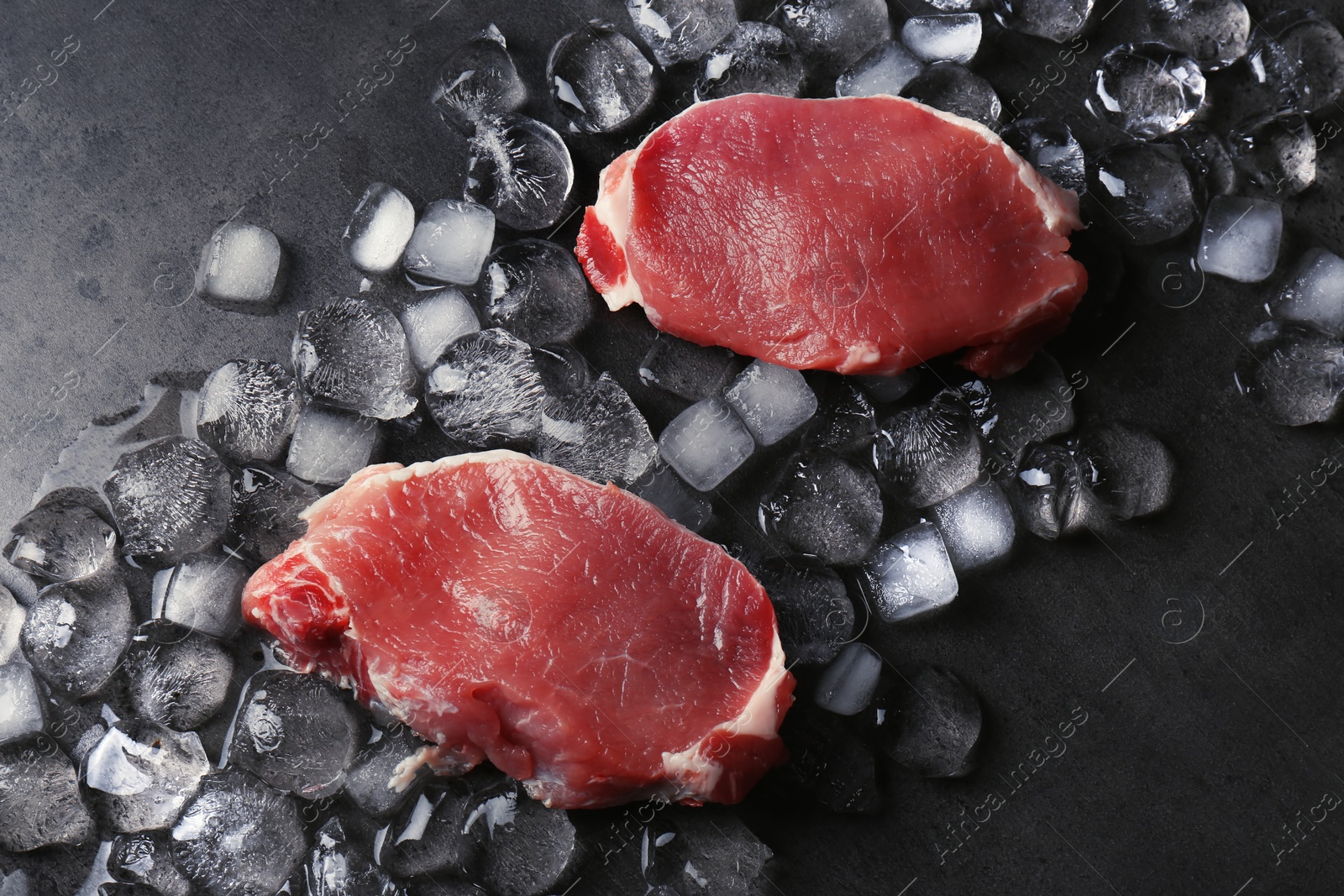 Photo of Flat lay composition with raw meat and ice cubes on dark background