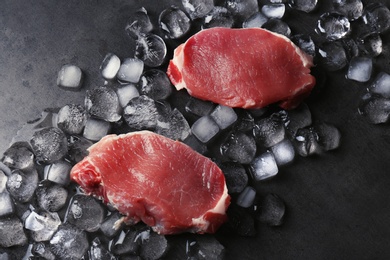 Flat lay composition with raw meat and ice cubes on dark background