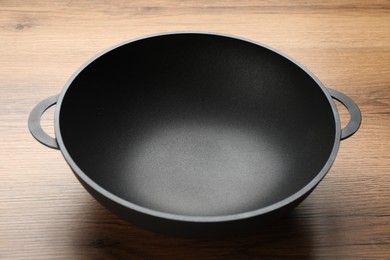Photo of Empty iron wok on wooden table. Chinese cookware