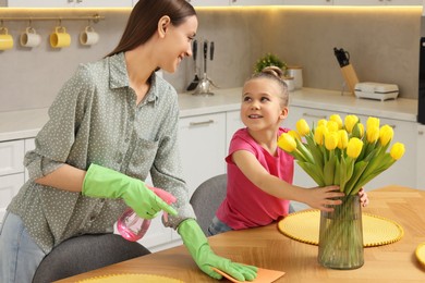 Photo of Spring cleaning. Mother and daughter tidying up in kitchen