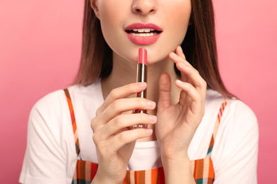 Beauty blogger with lipstick on pink background, closeup