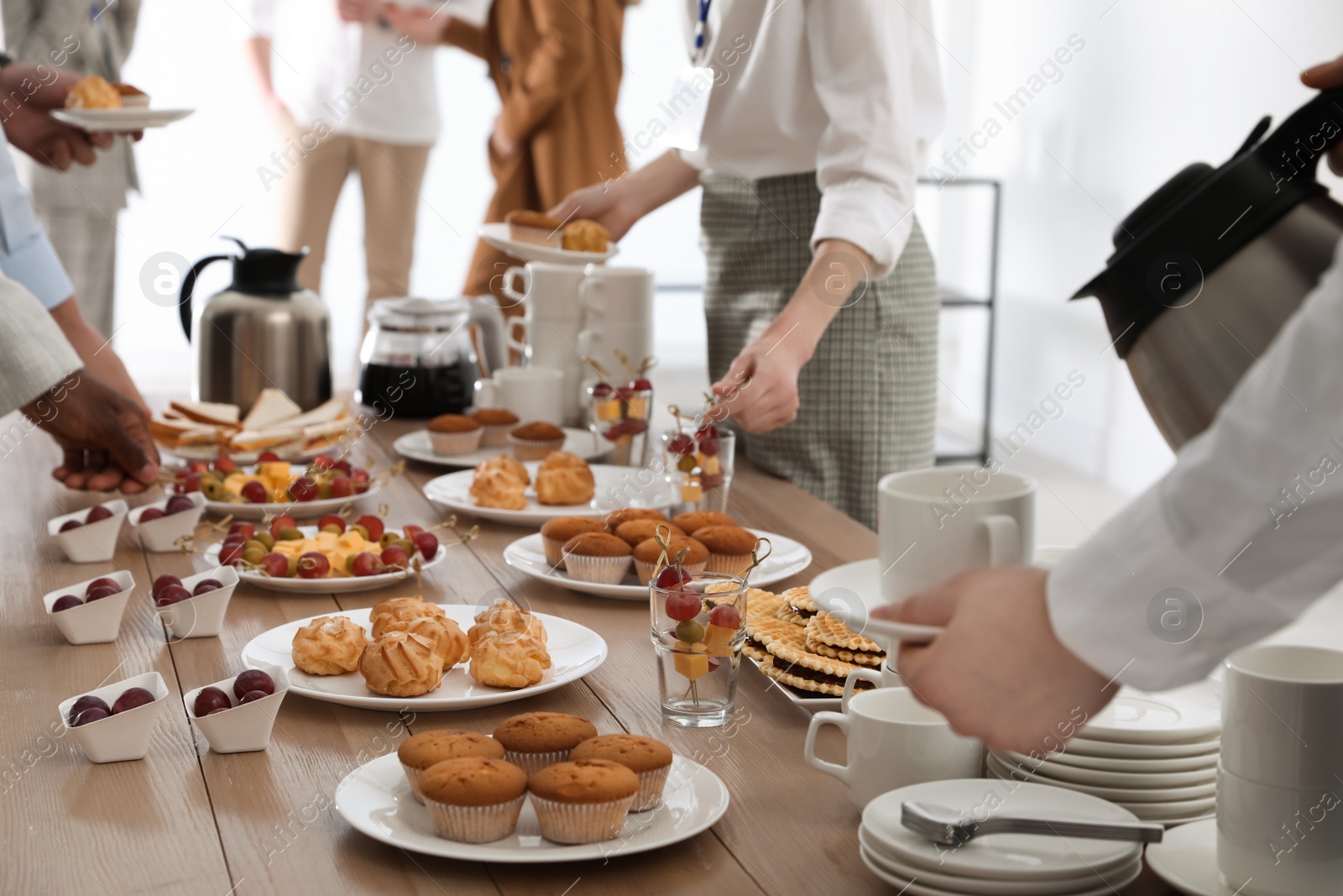 Photo of People near table with different delicious snacks during coffee break, closeup