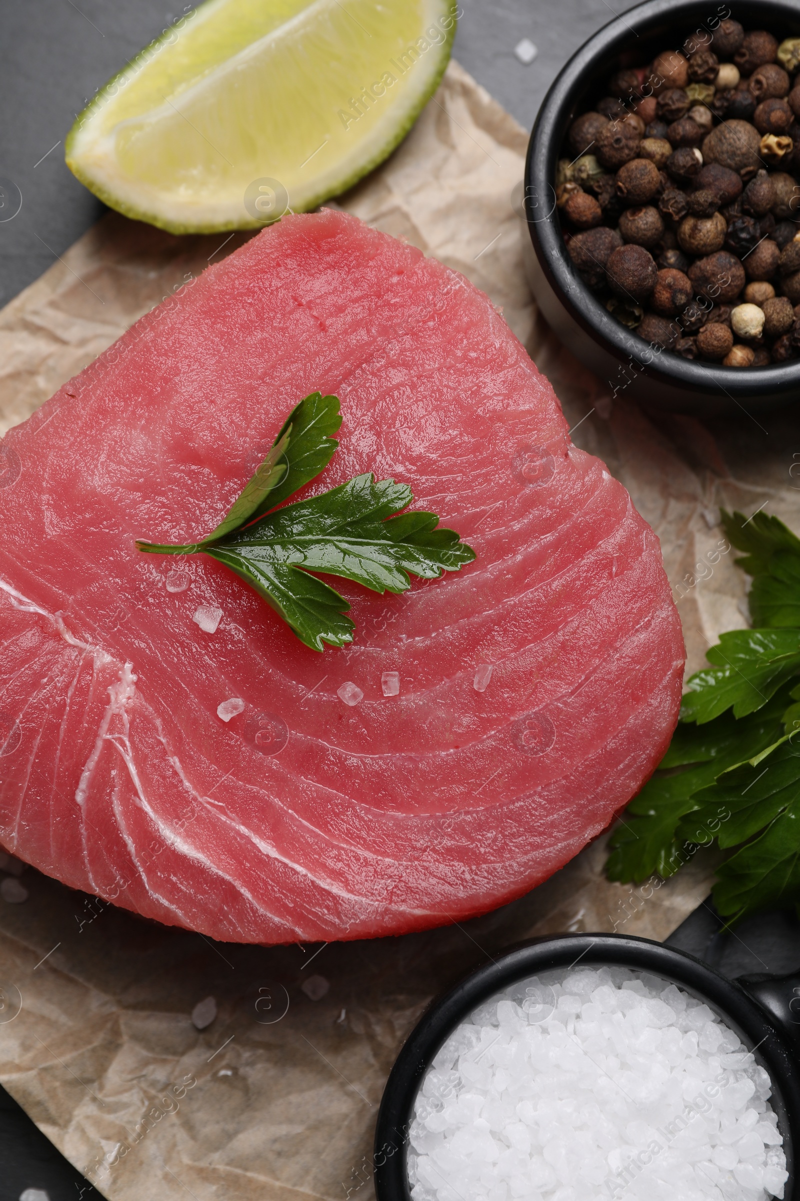 Photo of Raw tuna fillet, parsley and spices on table, flat lay