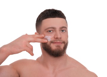 Handsome man applying cream onto his face on white background