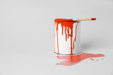 Photo of Can of orange paint and brush on white background. Space for text