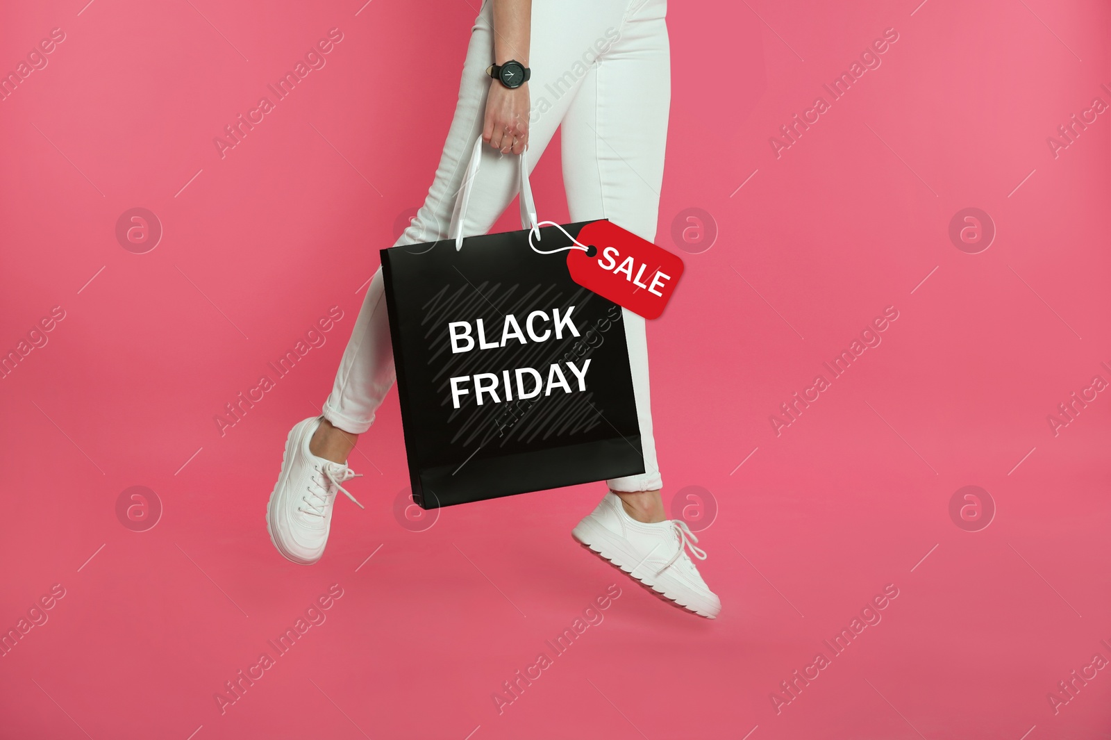 Image of Woman jumping with shopping bag on pink background, closeup. Black Friday Sale