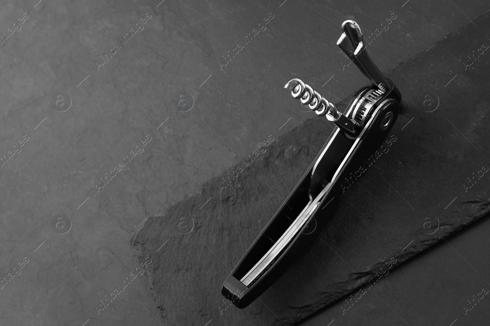 Photo of One corkscrew (sommelier knife) on grey textured table, space for text