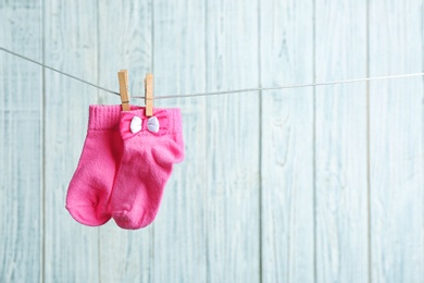 Photo of Pair of socks on laundry line against wooden background, space for text. Baby accessories