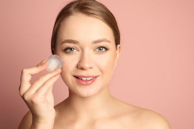 Photo of Young woman with ice cube on color background. Skin care