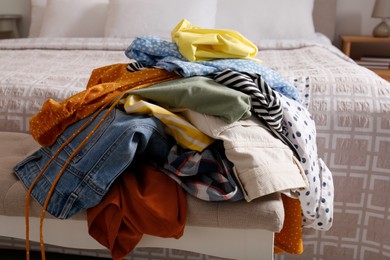 Photo of Messy pile of dirty clothes on indoor bench in bedroom. Tidying up method